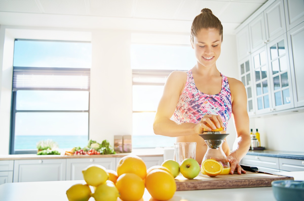 Fit smiling young woman preparing healthy fruit juice