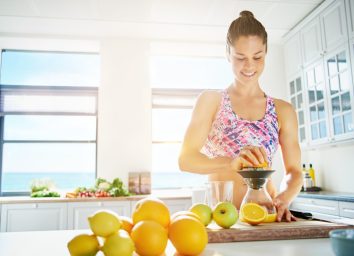 Fit smiling young woman preparing healthy fruit juice