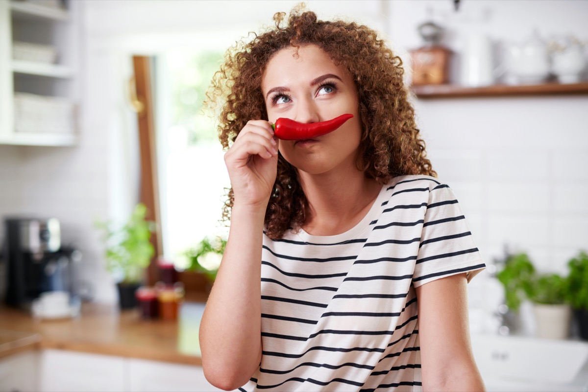 Woman using chili pepper as a funny mustache