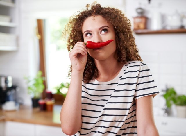 Woman using chili pepper as a funny mustache