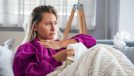 Woman experiencing first Covid-19 symptoms throat pain breathing problems on sofa