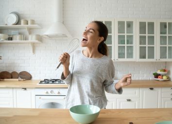 Happy woman singing in her kitchen