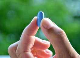 Hand of man holding blue pill.