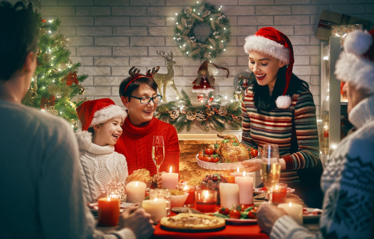 Happy family are having dinner at home. Celebration holiday and togetherness near tree.