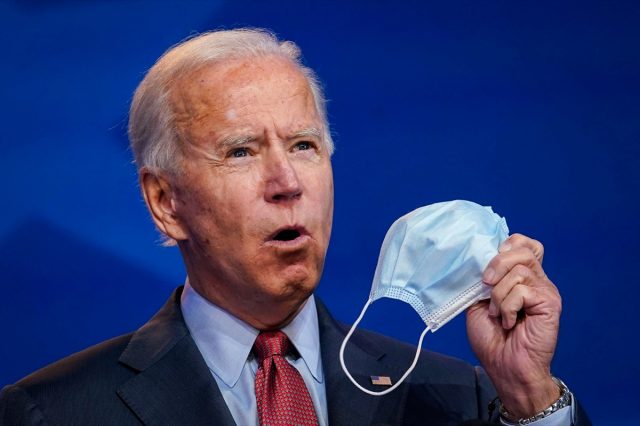 Joe Biden holds up a face mask while giving remarks about the Affordable Care Act and Covid-19.