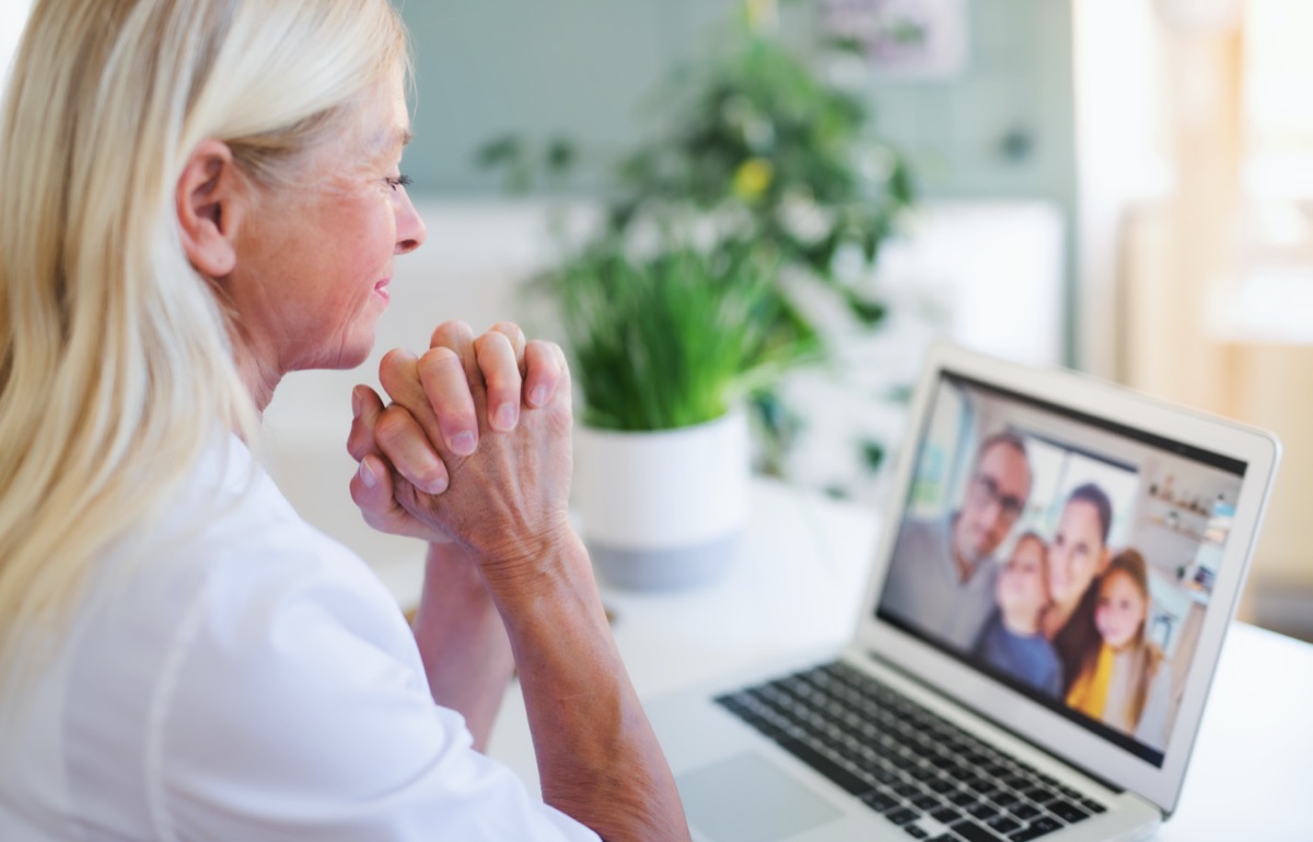 Senior woman with laptop indoors at home, family video call concept.