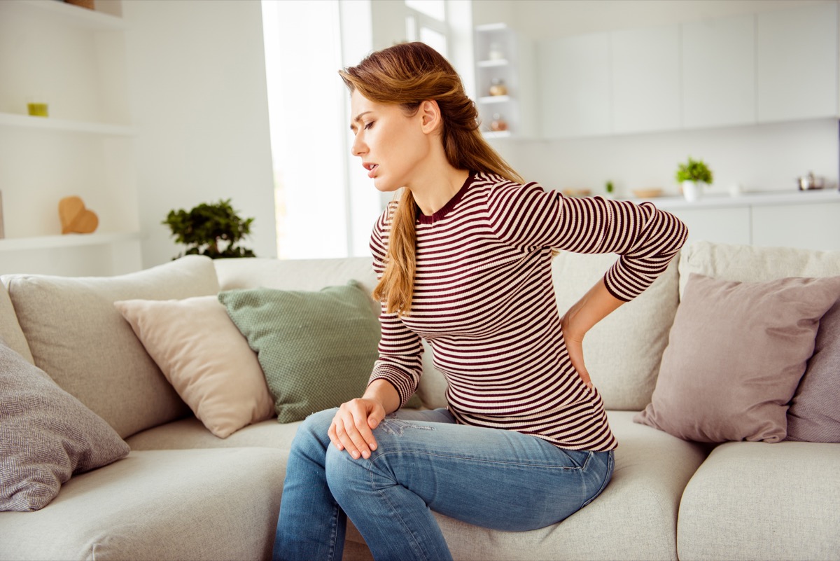 Woman's hands hold back spine suffering pain wear.