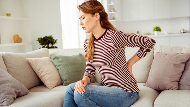Woman's hands hold back spine suffering pain wear.
