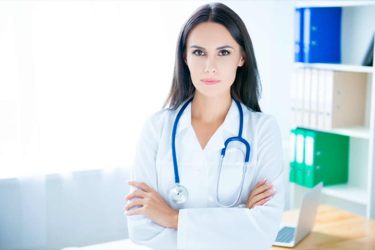 Portrait of serious young doctor in hospital with crossed hands