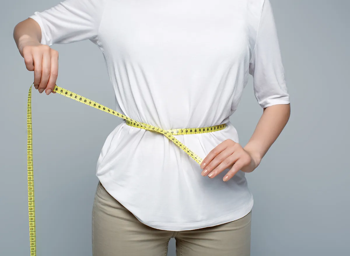 Measuring tape, stomach and woman in studio for wellness, weight