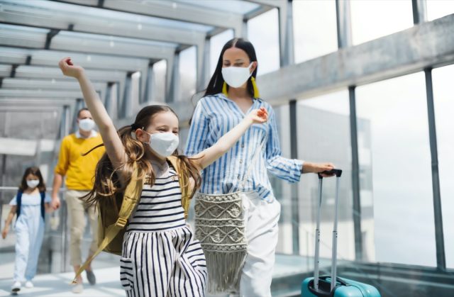 A family with two children wears a mask and goes on vacation at the airport.