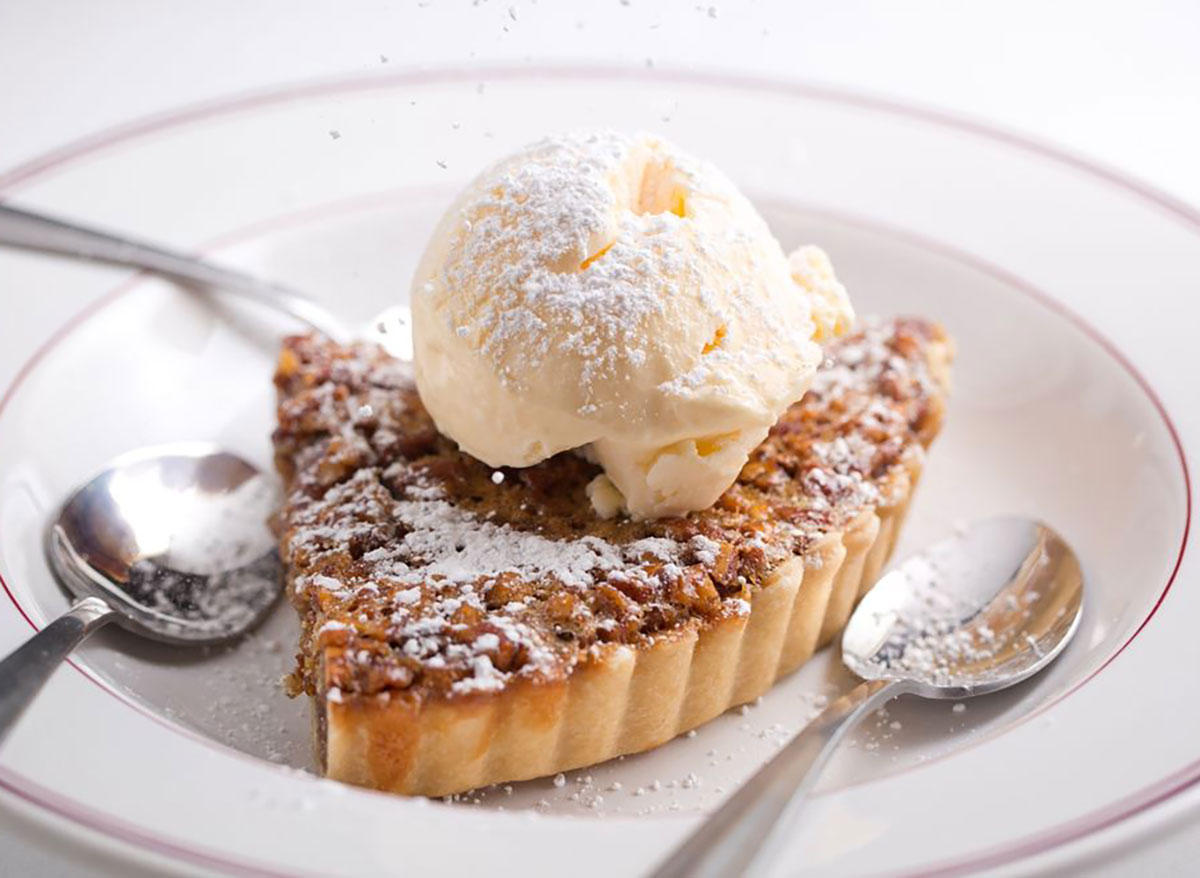 pecan pie slice on a plate topped with ice cream
