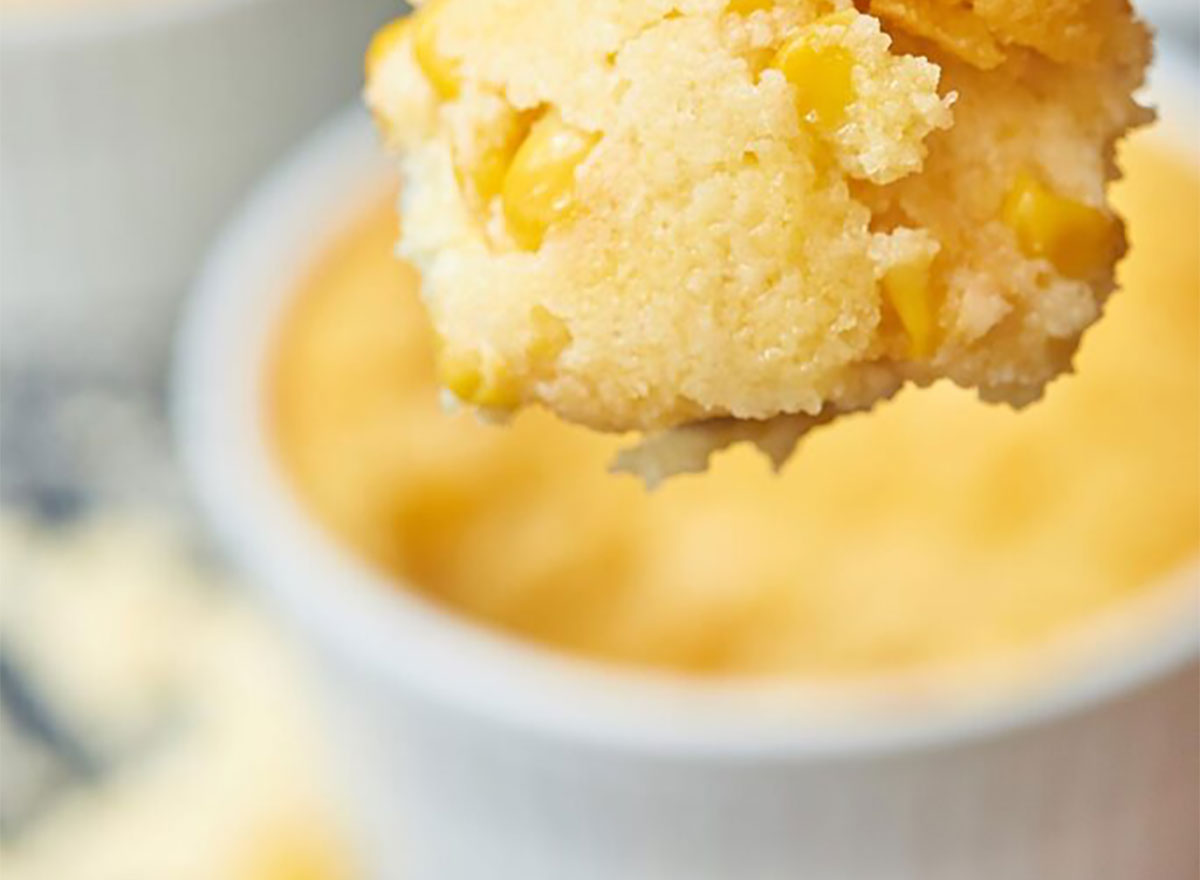 corn casserole in white ramekin with spoon