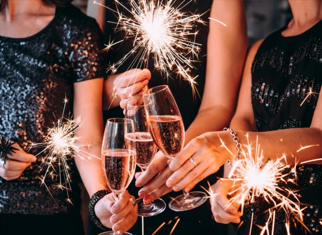 Friends celebrating Christmas or New Year eve party with Bengal lights and rose champagne.