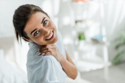 beautiful smiling girl looking at camera in bedroom in the morning