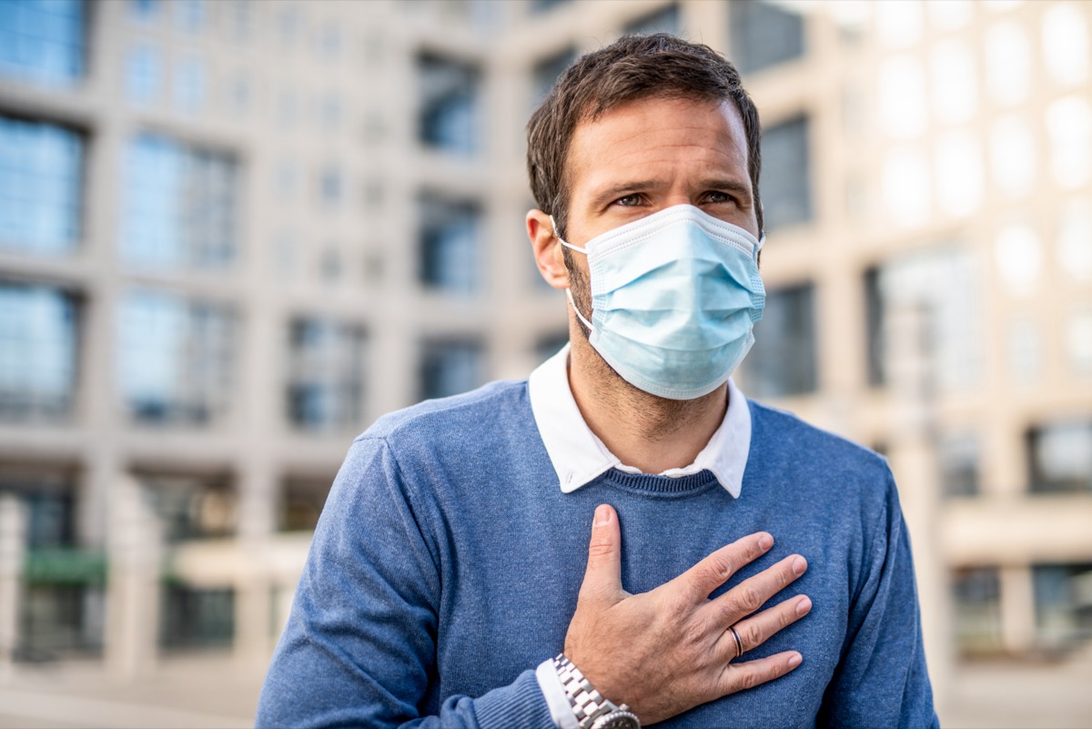 Man having a chest pain and wearing a protection mask.