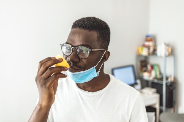 Man taking off face mask for smelling lemon