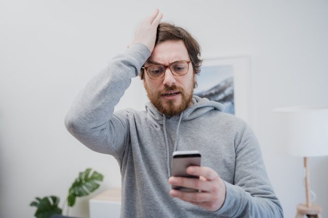 Upset frustrated man reading bad news on cell phone