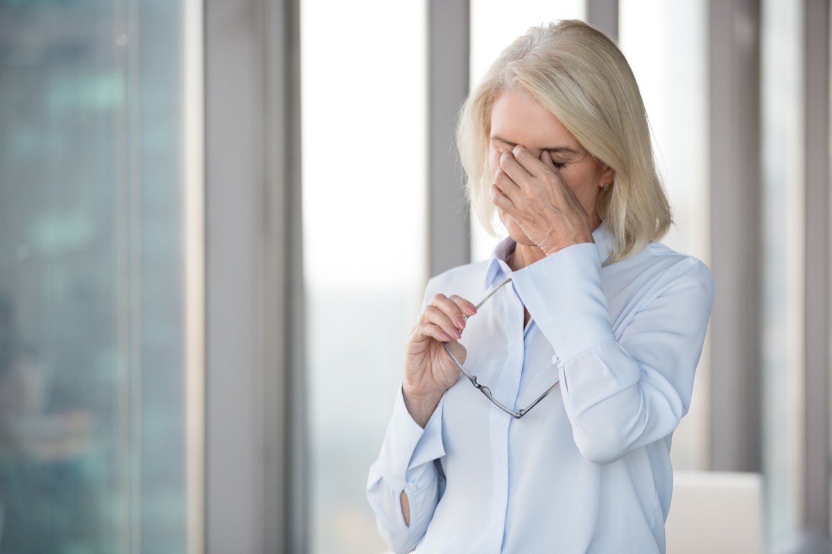 Une femme mûre fatiguée enlève ses lunettes et a mal à la tête