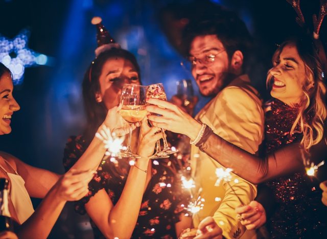 Group of friends having fun and holding sparklers at New Year's party