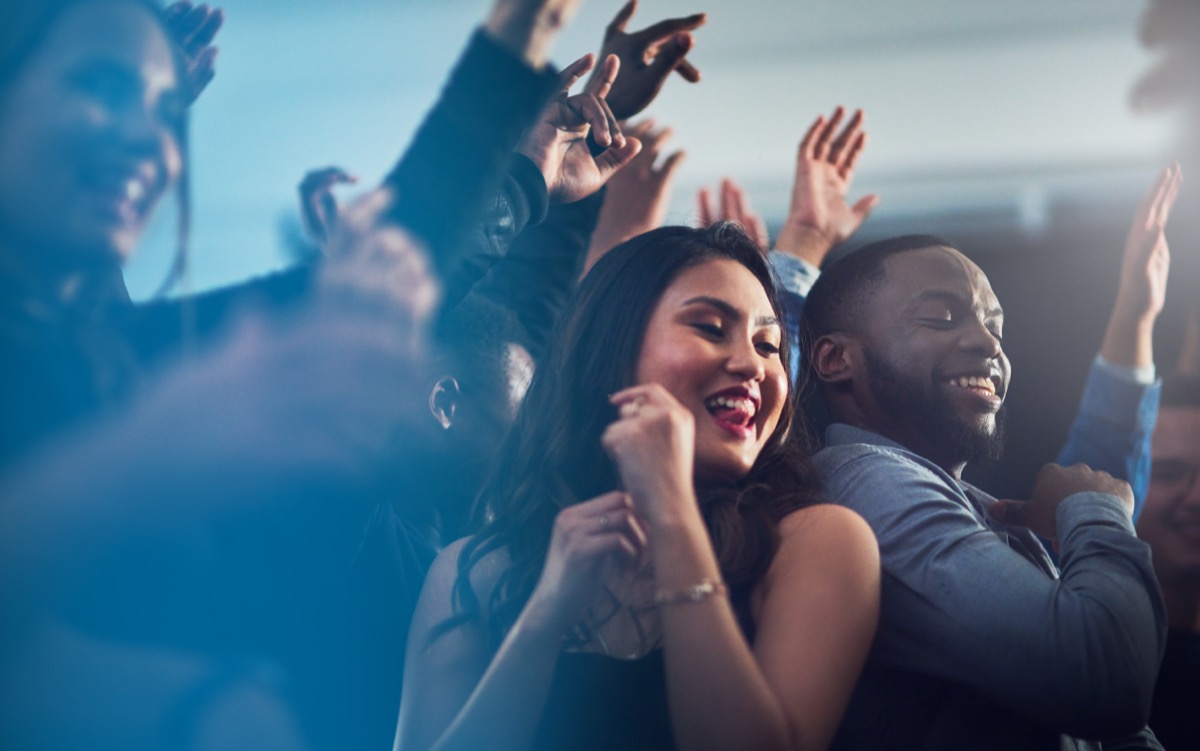 Energetic young couple dancing together at a party at night.