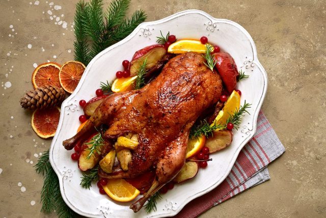 whole roast goose on serving platter with orange slices