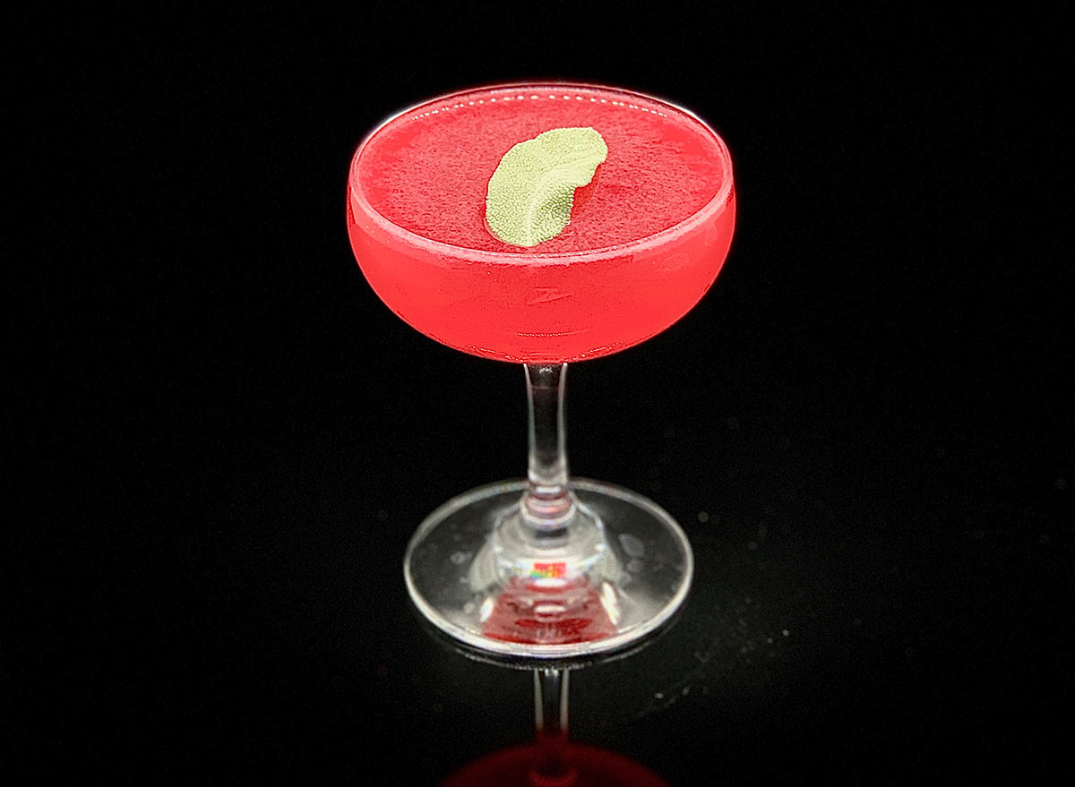 A pink and green nightcap cocktail drink on a black background