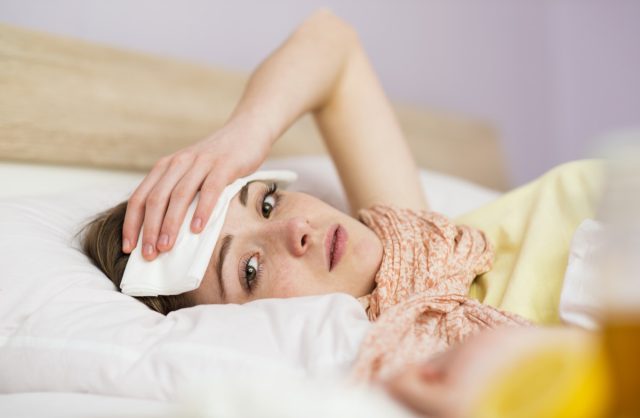 Mujer enferma acostada en la cama con fiebre alta.