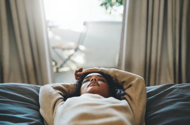 Woman lying on her bed with her eyes closed.