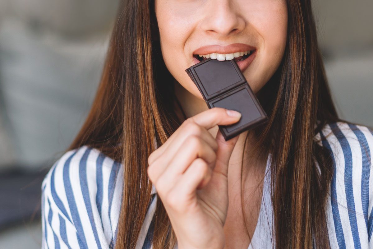woman eating bite of chocolate bar