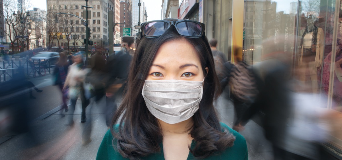 Woman in crowd wearing surgical mask.