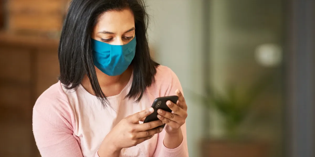 Woman with face protective mask looking at phone.