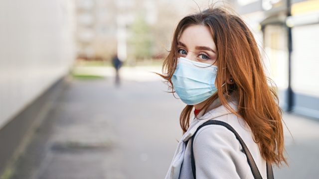 Young woman with beautiful blue eyes and disheveled hair wearing protection face mask against coronavirus MERS-Cov, Novel coronavirus 2019-nCoV. Concept of coronavirus quarantine and pandemic.
