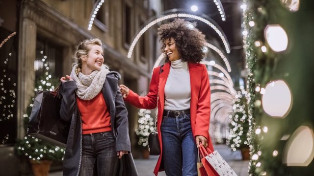 Women Friends Smiling Broadly In Cheerful Manner Having Fun At Shopping Mall, Buying Christmas Gifts