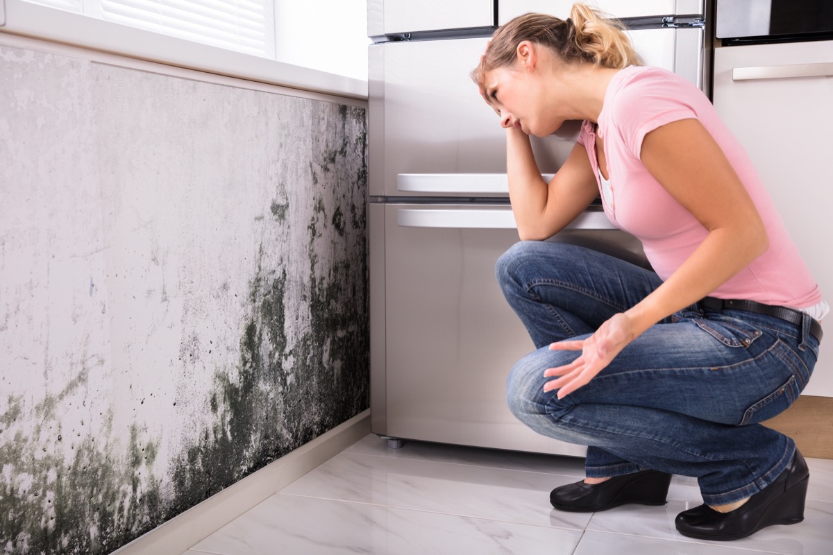 Shocked woman looking at mold on the wall.