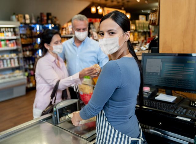 Cashier working at the supermarket wearing a facemask while scanning products