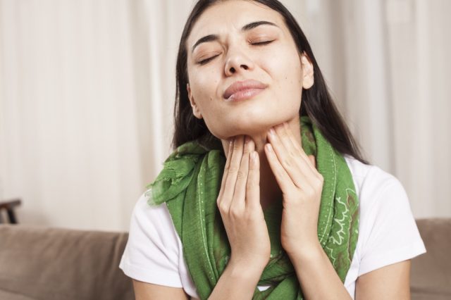 Woman touches her throat.