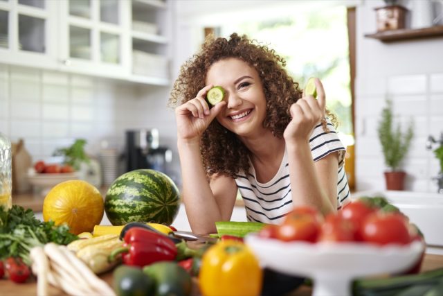 Woman holding a slice of cucumber