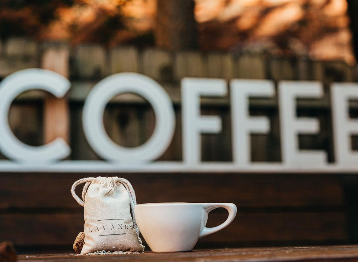 bag of coffee beans and coffee mug in front of decorative sign