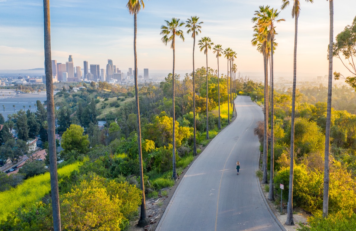 Drone shot of a woman walking down a street toward Downtown Los Angeles.