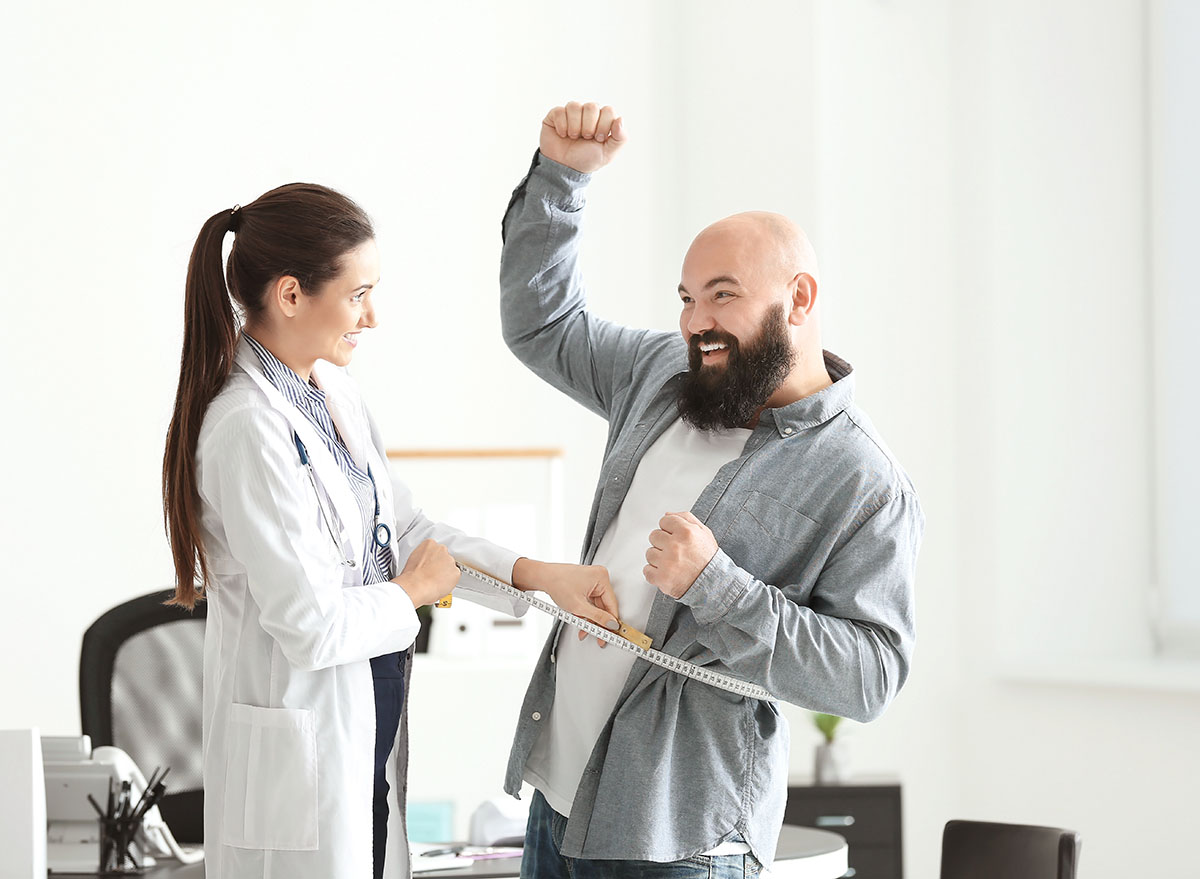 female doctor checking male patient weight