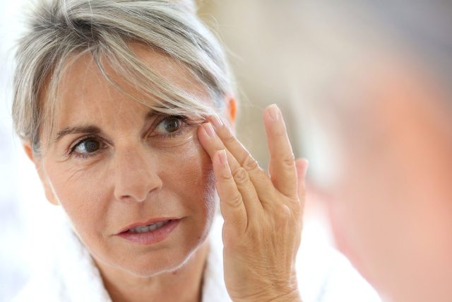 older woman touching wrinkles on face