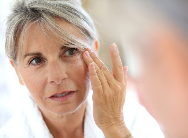 older woman touching wrinkles on face
