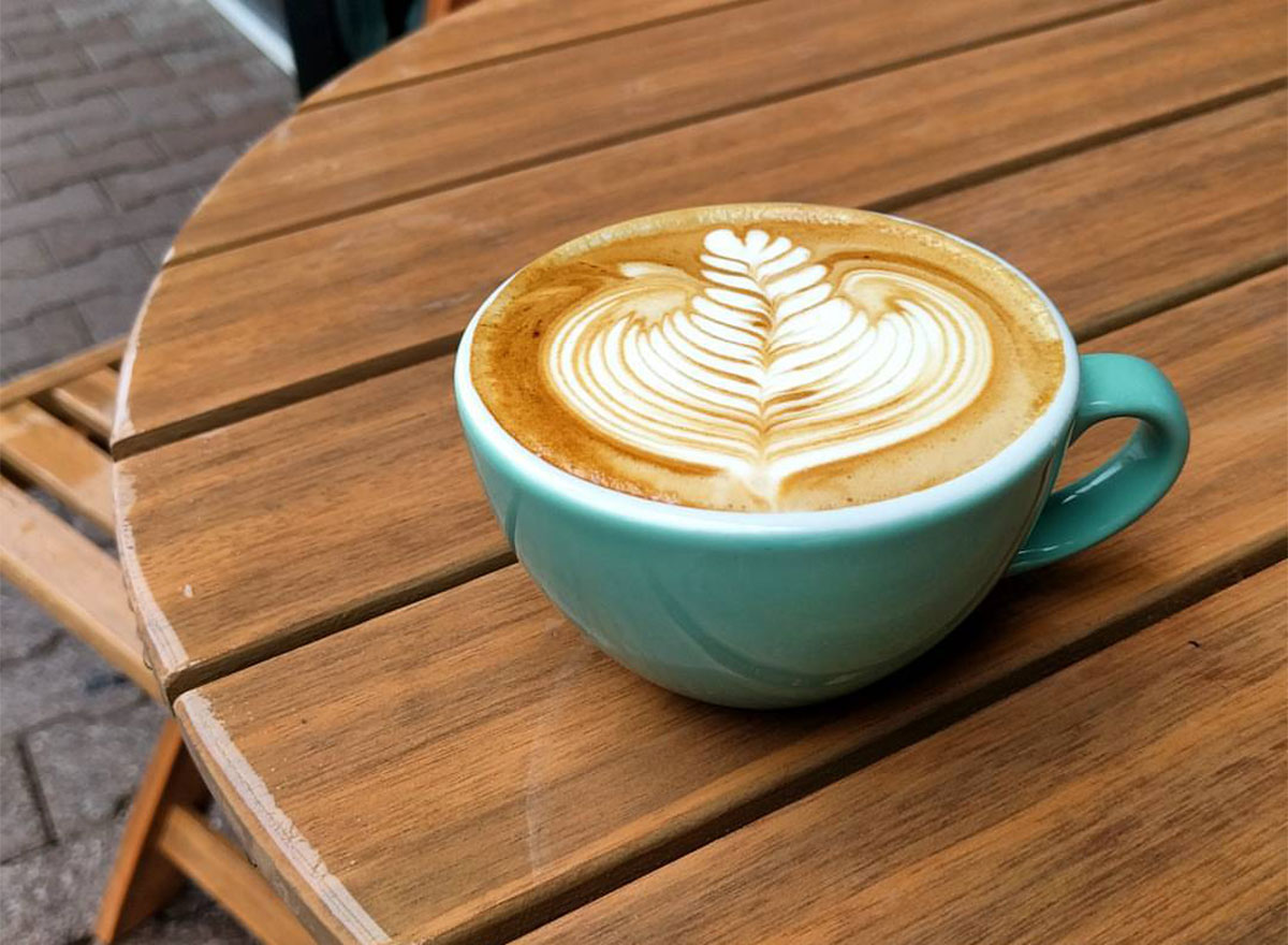 mug with latte art on wooden picnic table