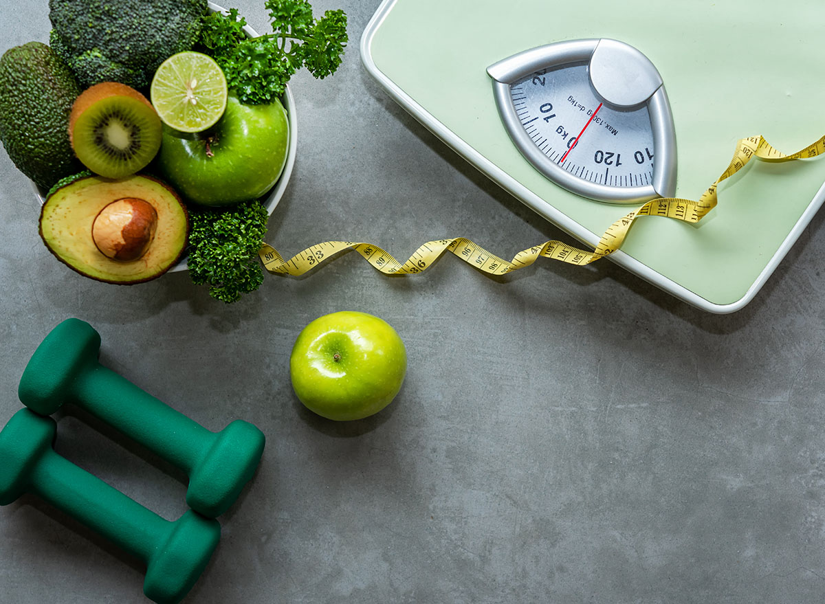 scale with weights measuring tape and bowl of healthy foods