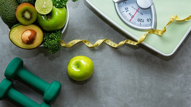 scale with weights measuring tape and bowl of healthy foods