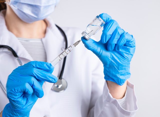 Doctor holding syringe, medical injection in hand with glove.