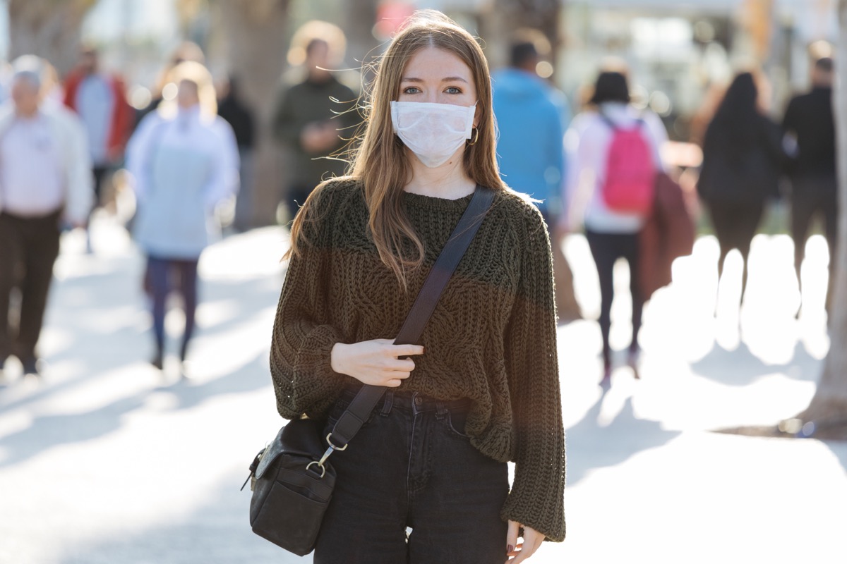 Woman wearing face mask on a busy street.
