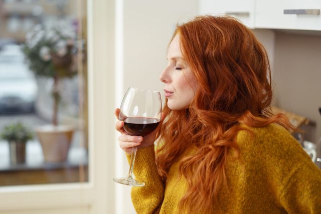 femeie care bea alcool din vin acasă