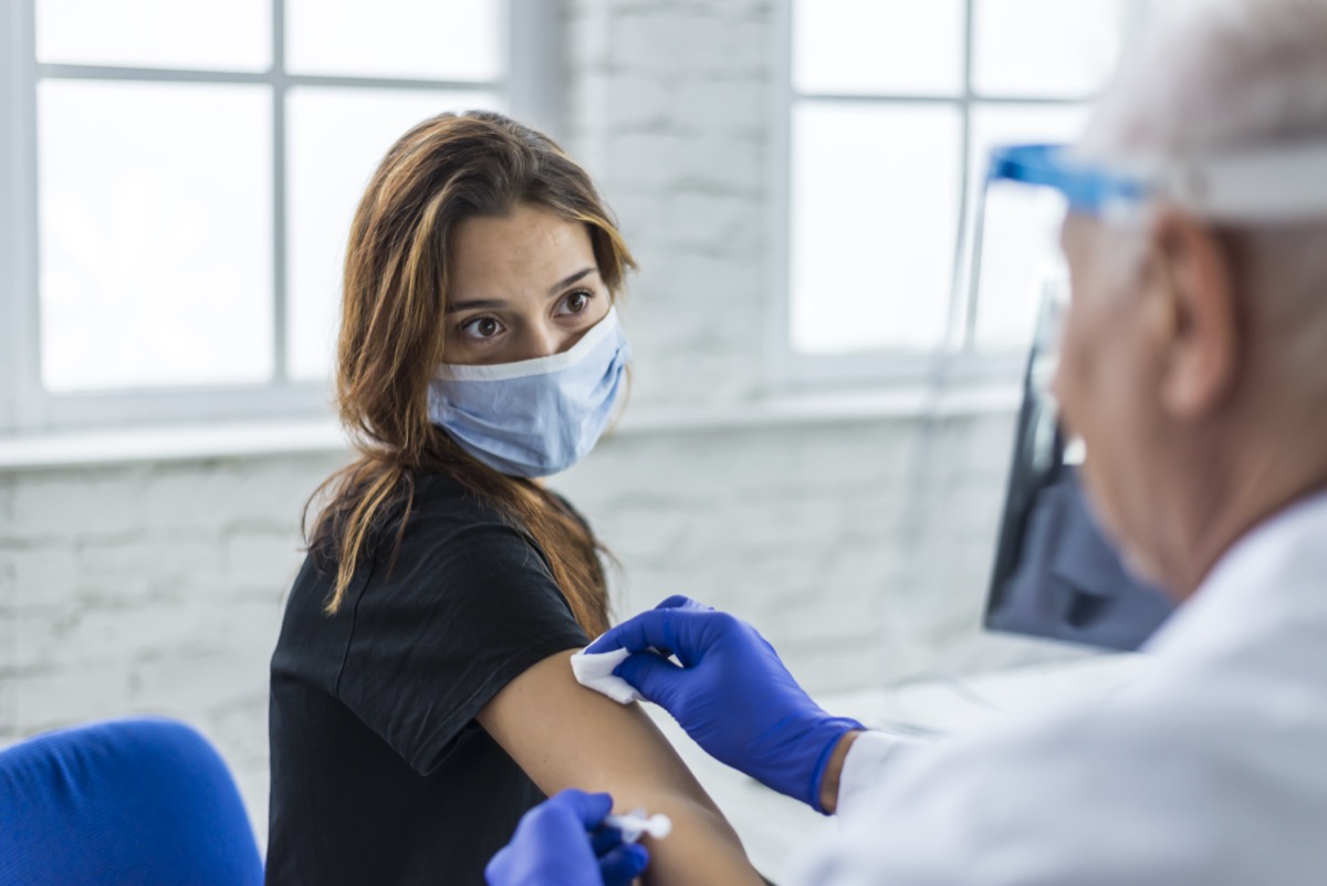 Young woman taking a vaccine from her doctor.